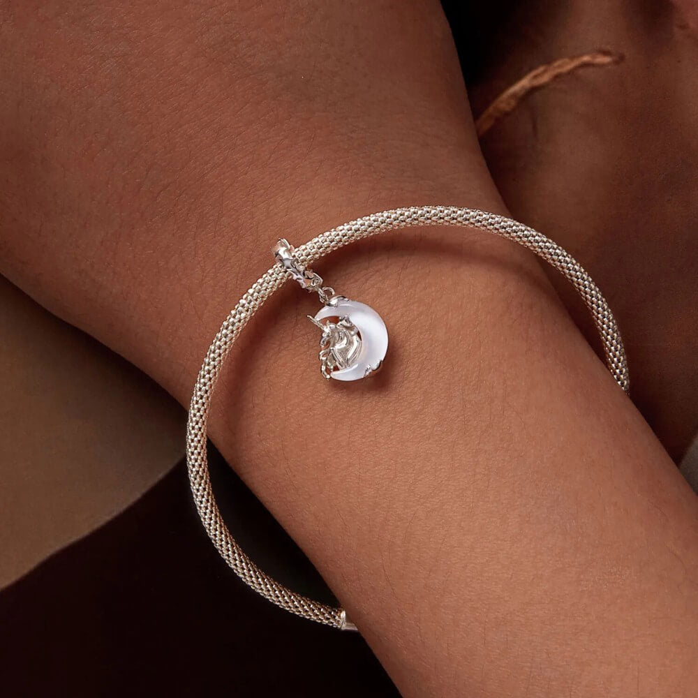 Sterling silver unicorn charm on moon with opalescent glow.