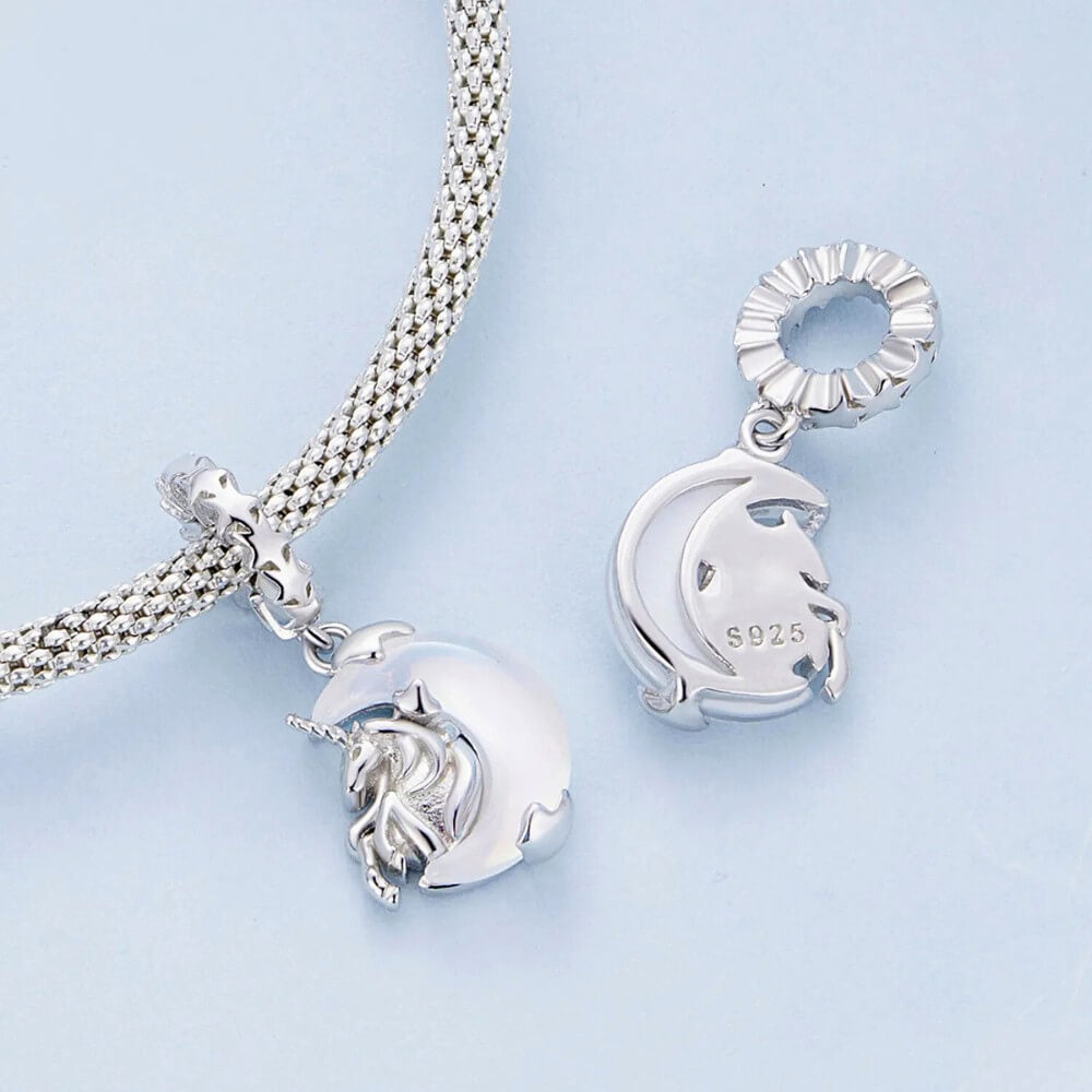 Sterling silver unicorn charm on moon with opalescent glow.