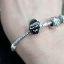 Sterling silver mother and baby charm with iridescent heart detail.