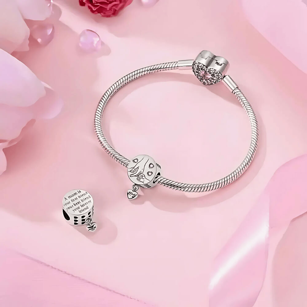 Sterling silver round charm with engraved mother and child hands, pink crystal hearts, and dangling ‘Mom’ tag 