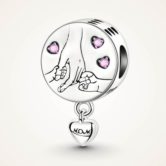 Sterling silver round charm with engraved mother and child hands, pink crystal hearts, and dangling ‘Mom’ tag – ORÉYA