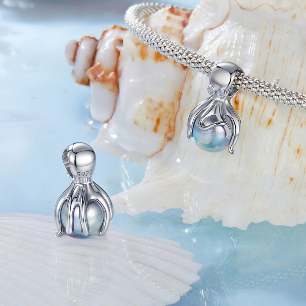 Sterling silver octopus charm holding iridescent pearl sphere.