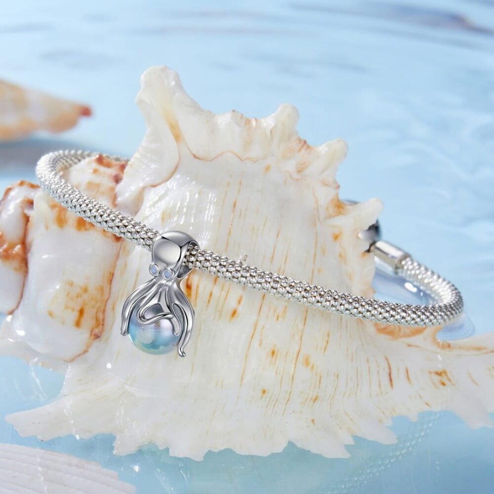 Sterling silver octopus charm holding iridescent pearl sphere.