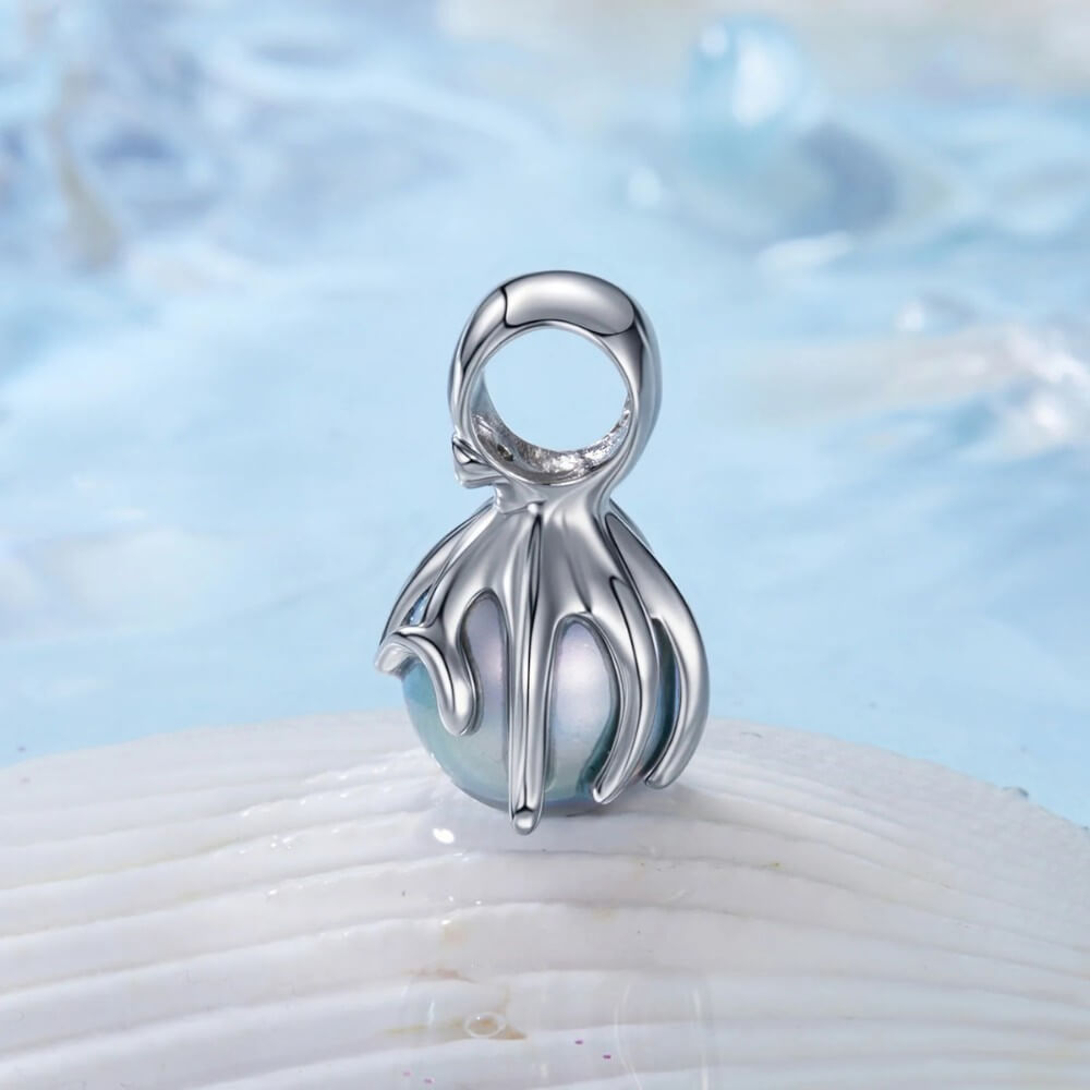 Sterling silver octopus charm holding iridescent pearl sphere.
