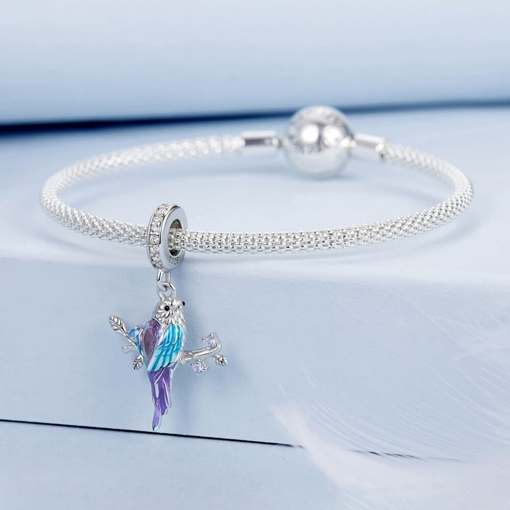 Silver bracelet with a colorful parrot charm on a light blue background