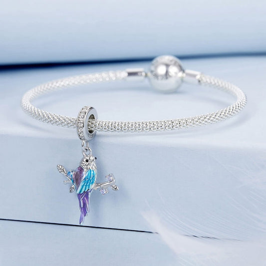 Silver bracelet with a colorful parrot charm on a light blue background