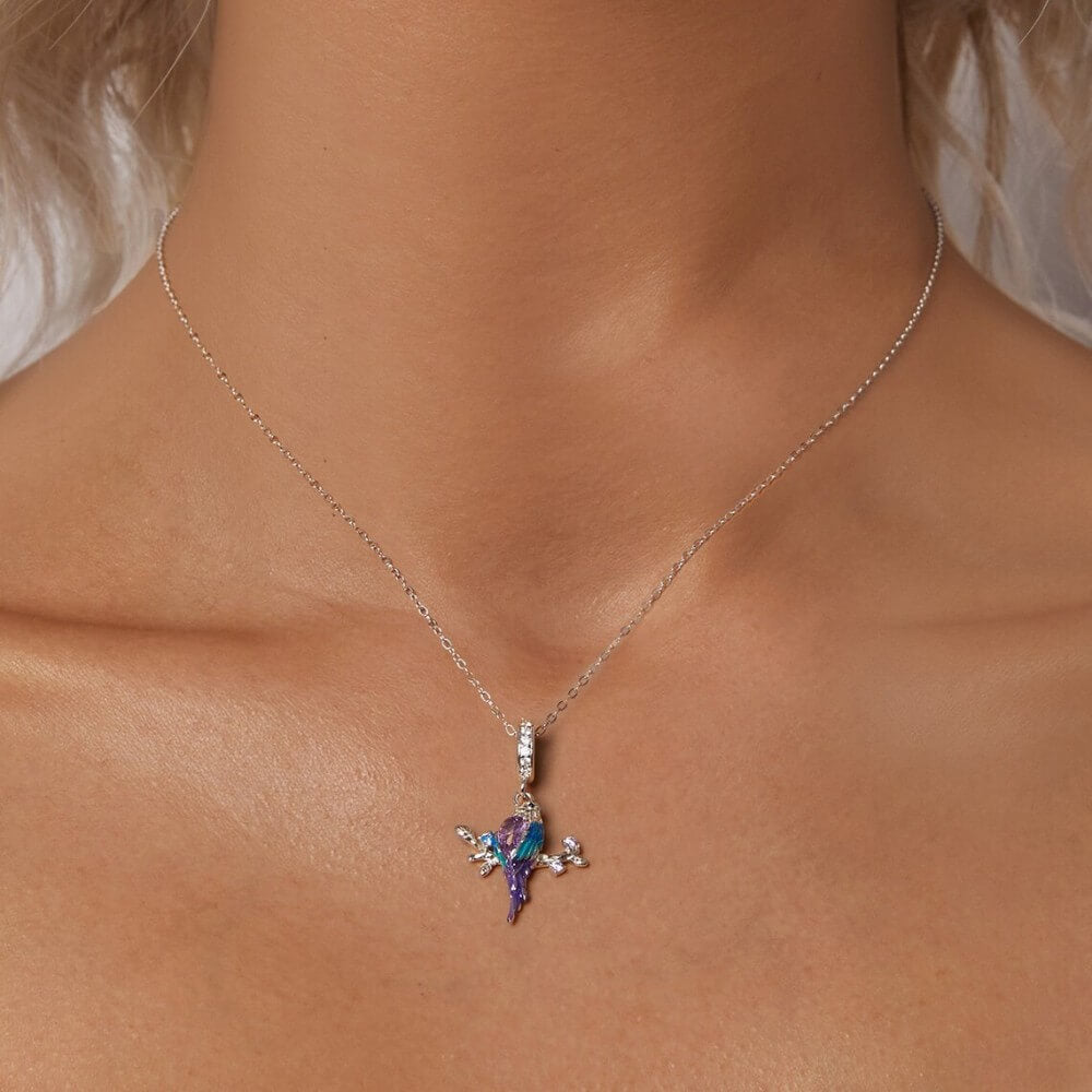 Sterling silver parrot charm with purple crystal, blue enamel, and branch details.