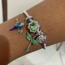 Sterling silver parrot charm with purple crystal, blue enamel, and branch details.