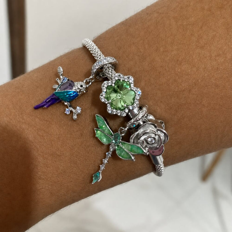 Sterling silver parrot charm with purple crystal, blue enamel, and branch details.