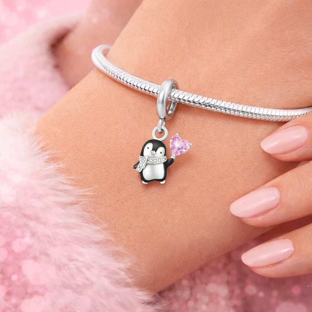 Sterling silver penguin charm holding pink heart crystal.