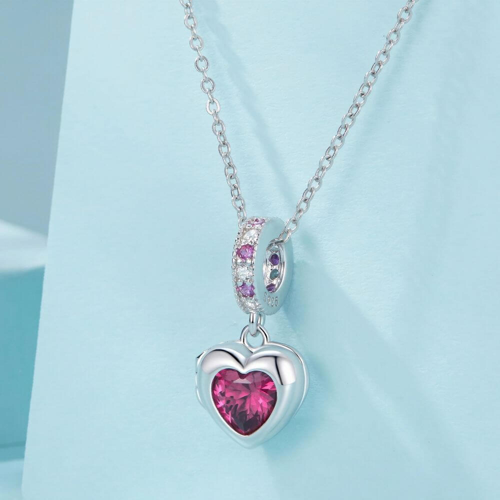 Sterling silver heart locket charm with deep pink crystal center and sparkling pink and clear stone details.