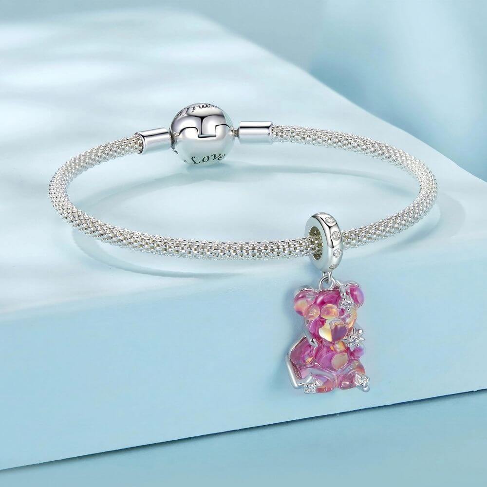Sterling silver pink teddy bear charm with iridescent finish, sparkling stars, and clear crystal accents.