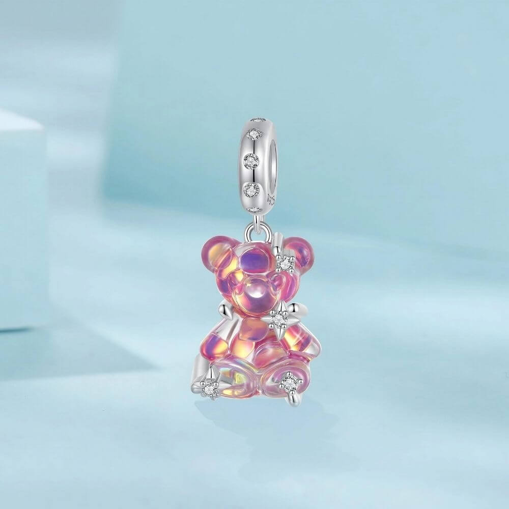 Sterling silver pink teddy bear charm with iridescent finish, sparkling stars, and clear crystal accents.