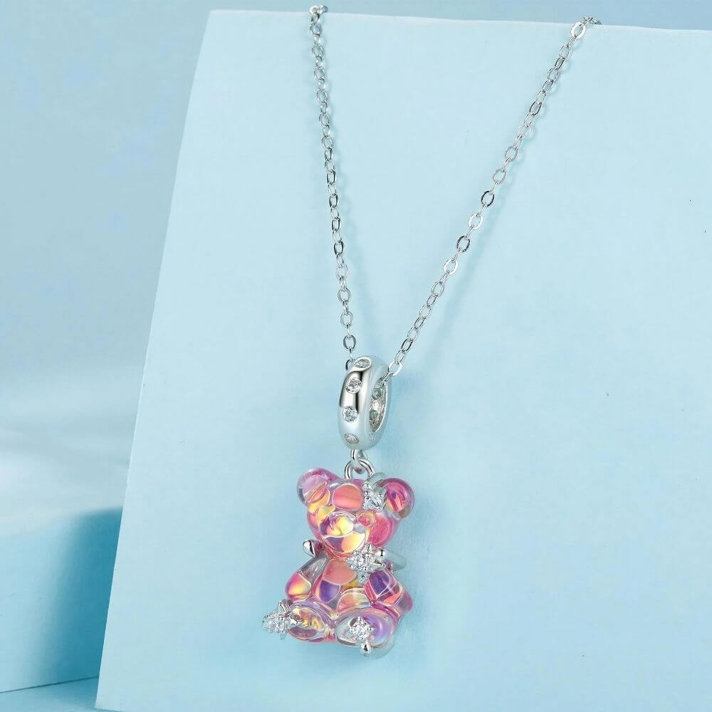 Sterling silver pink teddy bear charm with iridescent finish, sparkling stars, and clear crystal accents.