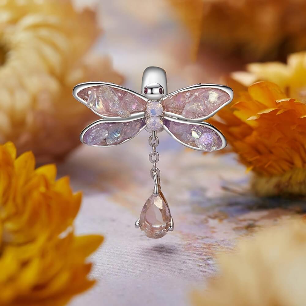 Dragonfly-shaped pendant with pink gemstones on a floral background