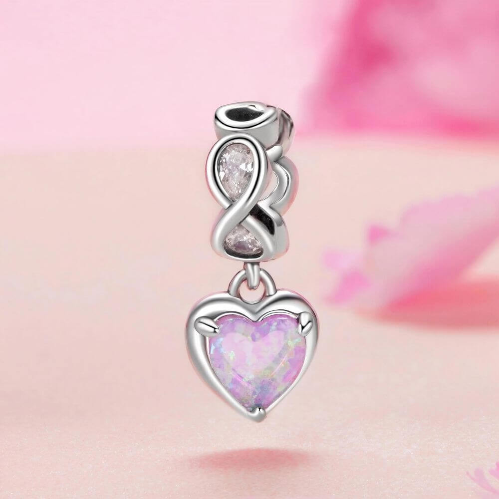 Sterling silver heart charm with pink opal center, infinity loop, and sparkling clear crystal details.