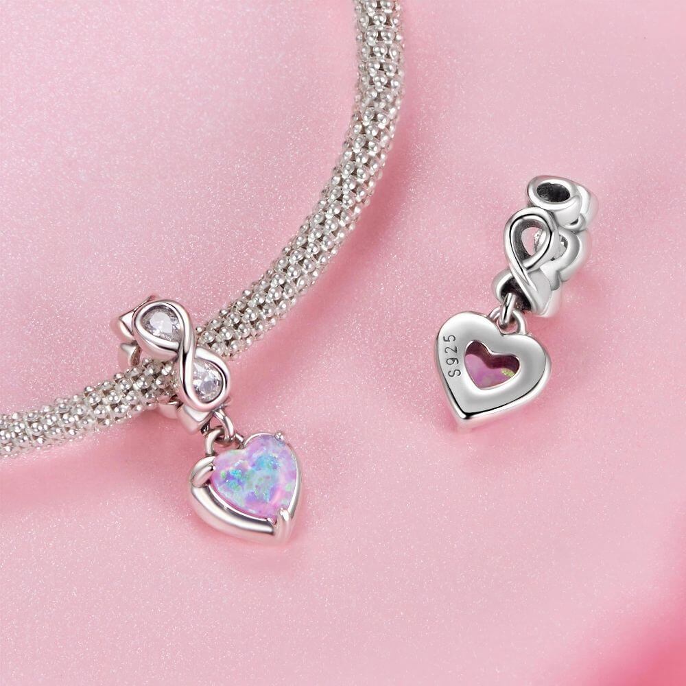 Sterling silver heart charm with pink opal center, infinity loop, and sparkling clear crystal details.