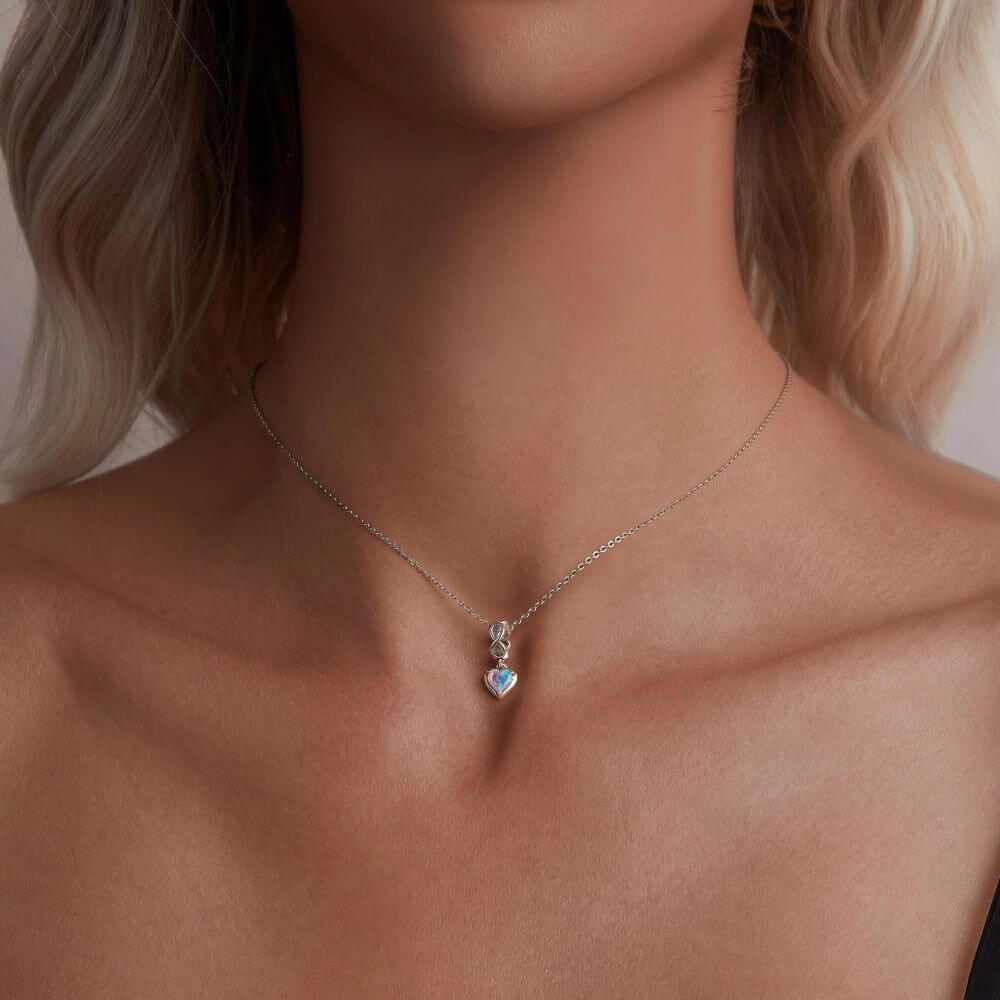 Sterling silver heart charm with pink opal center, infinity loop, and sparkling clear crystal details.