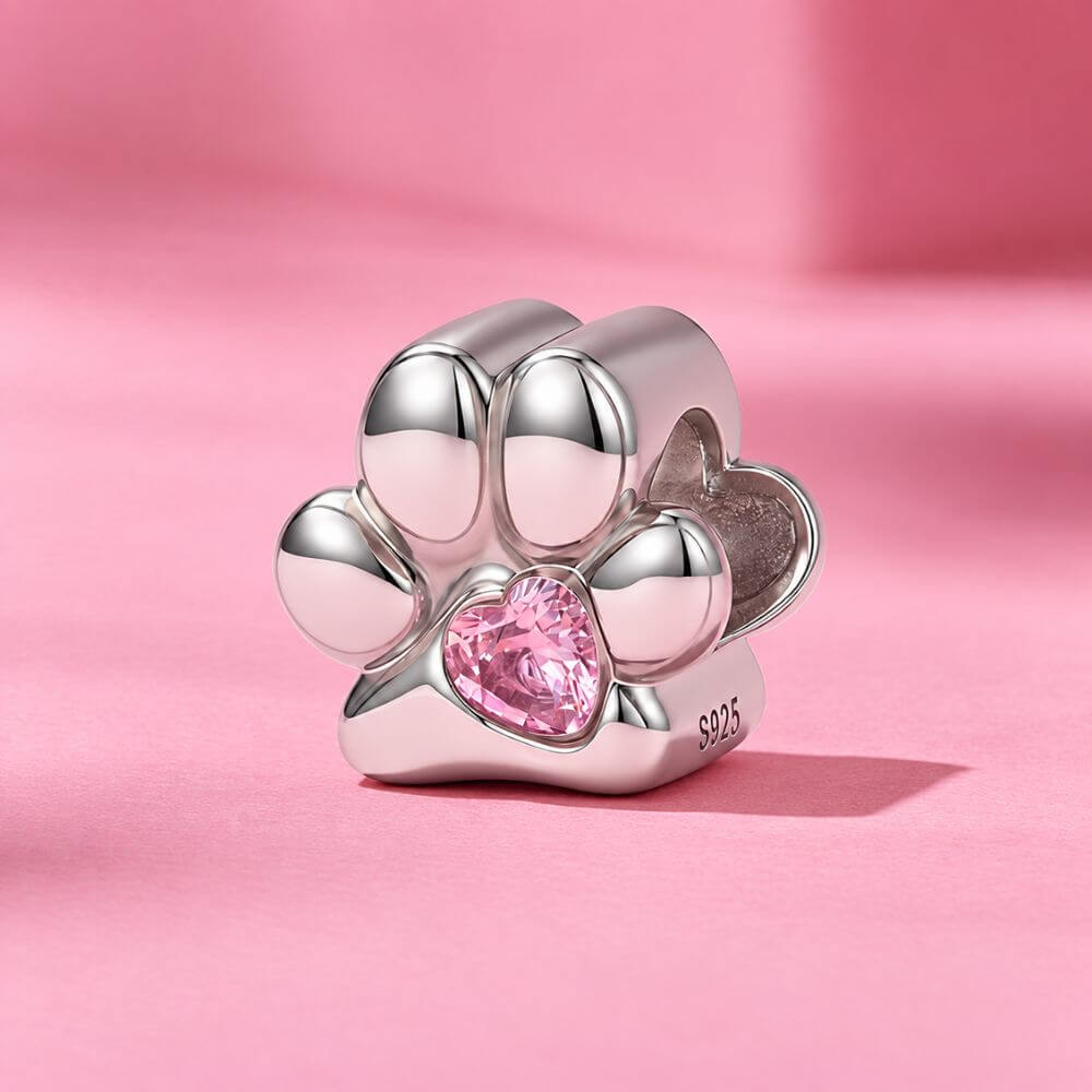 Sterling silver paw print charm with pink heart crystal center and polished pet-inspired details.