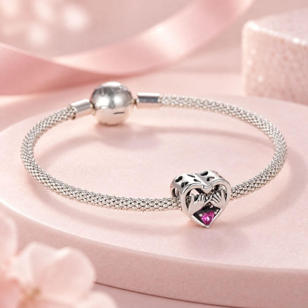 Sterling silver pinky promise charm with intertwined hands, pink heart crystal, and romantic heart frame.