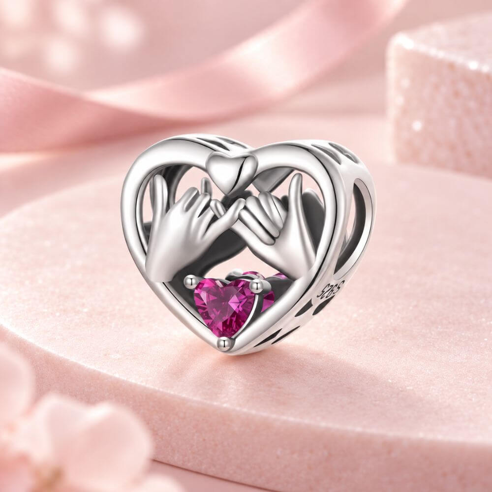 Sterling silver pinky promise charm with intertwined hands, pink heart crystal, and romantic heart frame.