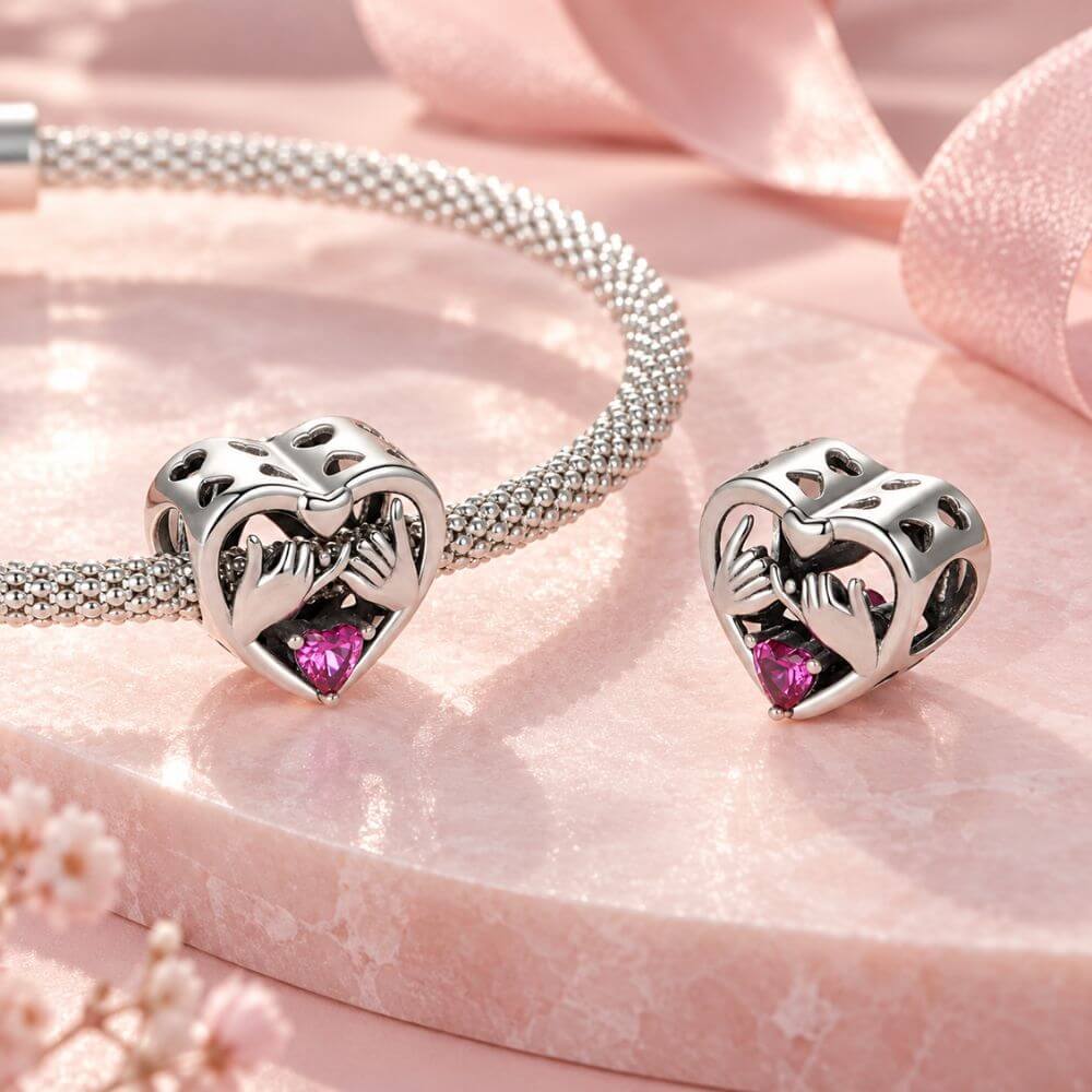 Sterling silver pinky promise charm with intertwined hands, pink heart crystal, and romantic heart frame.
