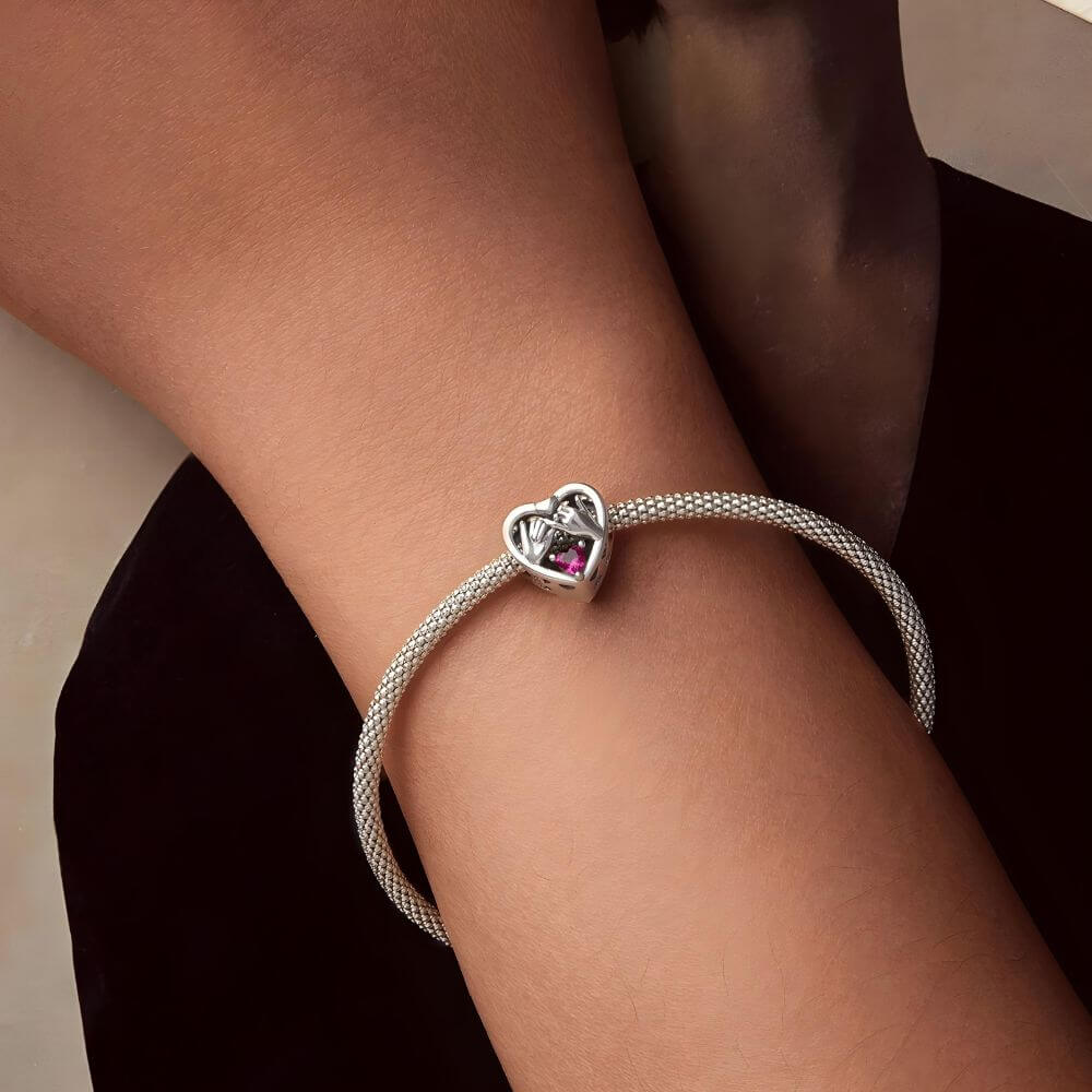 Sterling silver pinky promise charm with intertwined hands, pink heart crystal, and romantic heart frame.