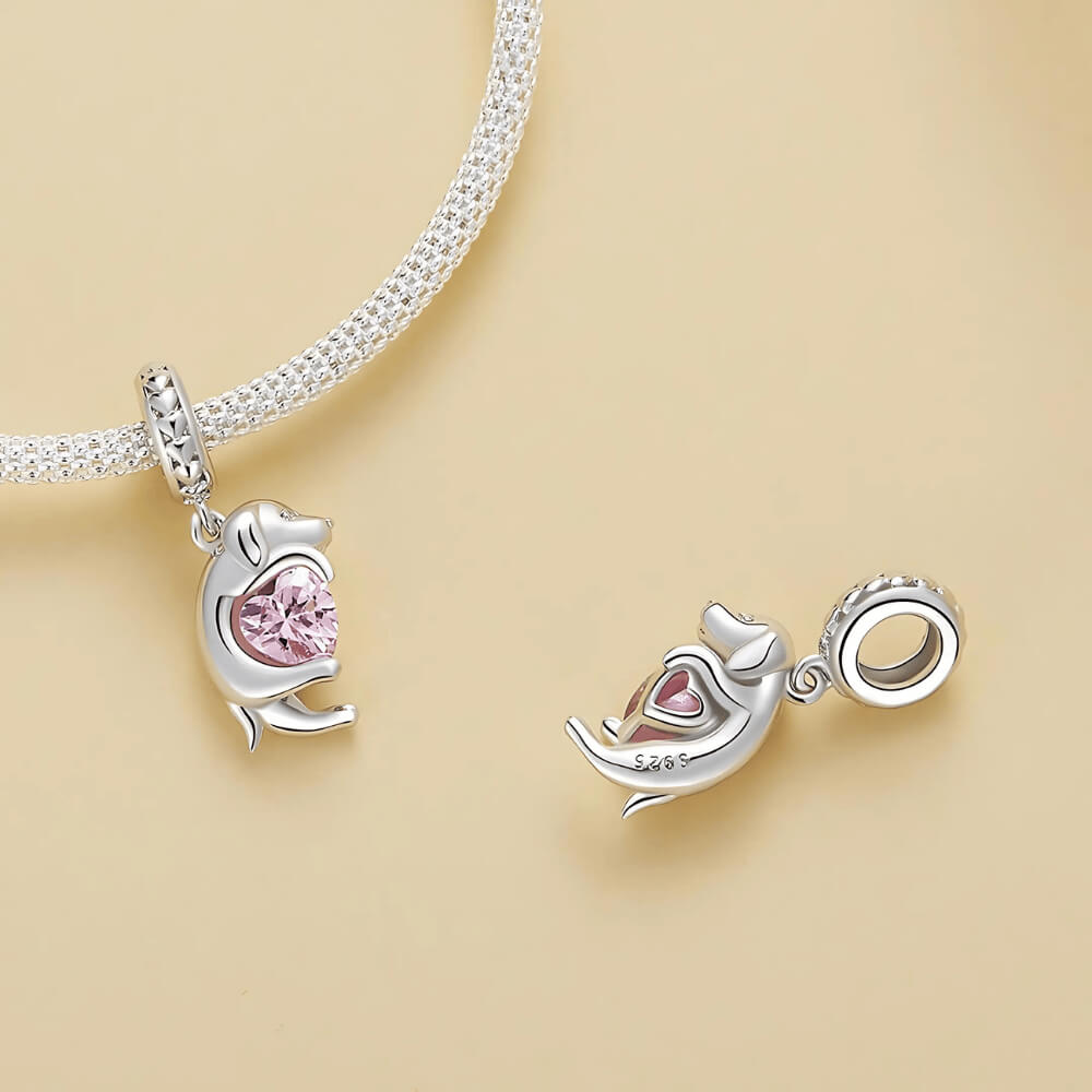 Sterling silver puppy charm hugging a pink heart-shaped stone 