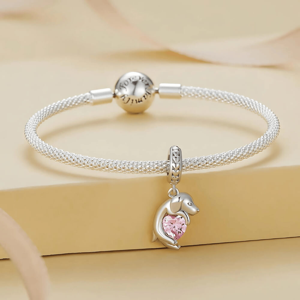 Sterling silver puppy charm hugging a pink heart-shaped stone 