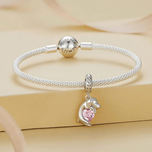 Sterling silver puppy charm hugging a pink heart-shaped stone 