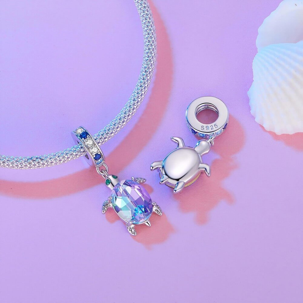 Sterling silver sea turtle charm with purple blue crystal shell and green eyes.