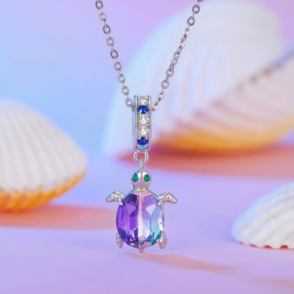 Sterling silver sea turtle charm with purple blue crystal shell and green eyes.