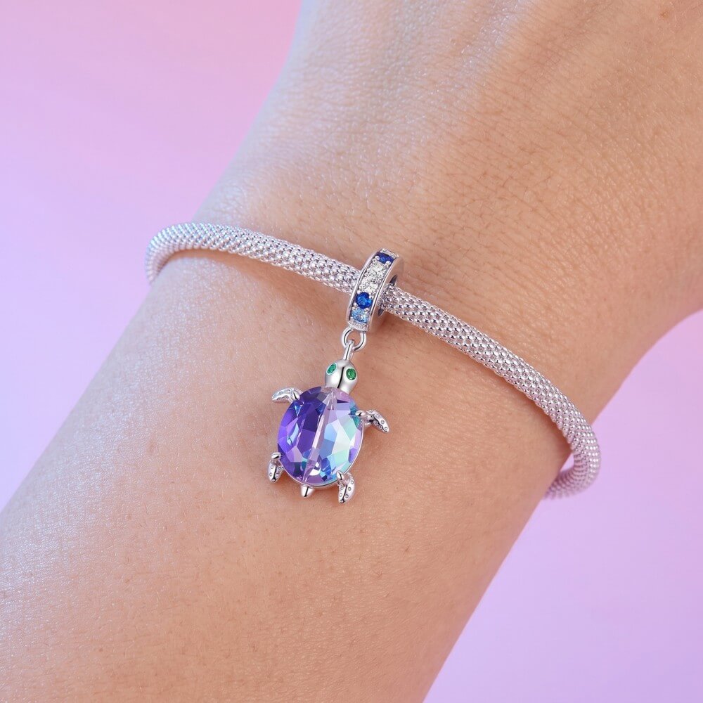 Sterling silver sea turtle charm with purple blue crystal shell and green eyes.