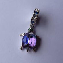Sterling silver sea turtle charm with purple blue crystal shell and green eyes.