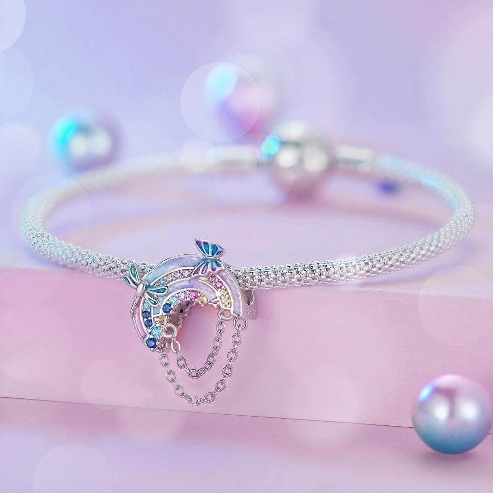 Sterling silver rainbow charm with colorful crystals, butterfly details, glitter enamel, and dangling safety chains.
