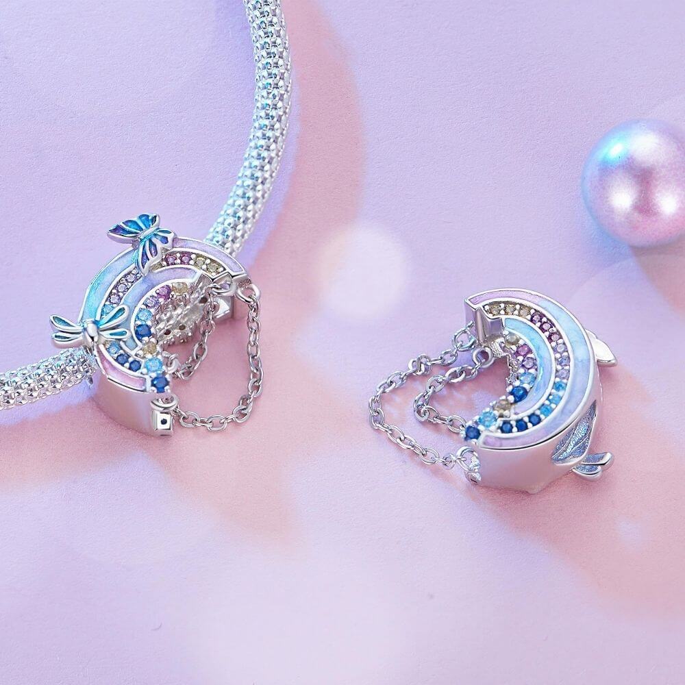 Sterling silver rainbow charm with colorful crystals, butterfly details, glitter enamel, and dangling safety chains.