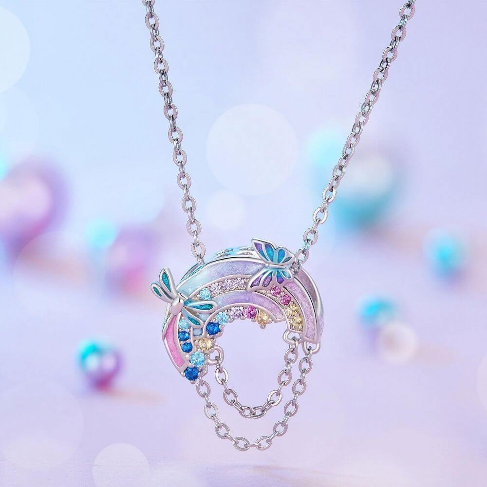 Sterling silver rainbow charm with colorful crystals, butterfly details, glitter enamel, and dangling safety chains.