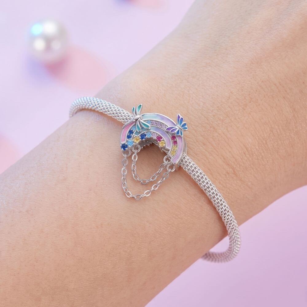 Sterling silver rainbow charm with colorful crystals, butterfly details, glitter enamel, and dangling safety chains.