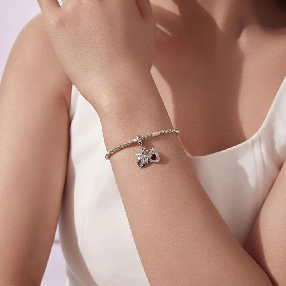 Sterling silver heart charm with red crystal center, floral details, stars, and a romantic double-heart design.