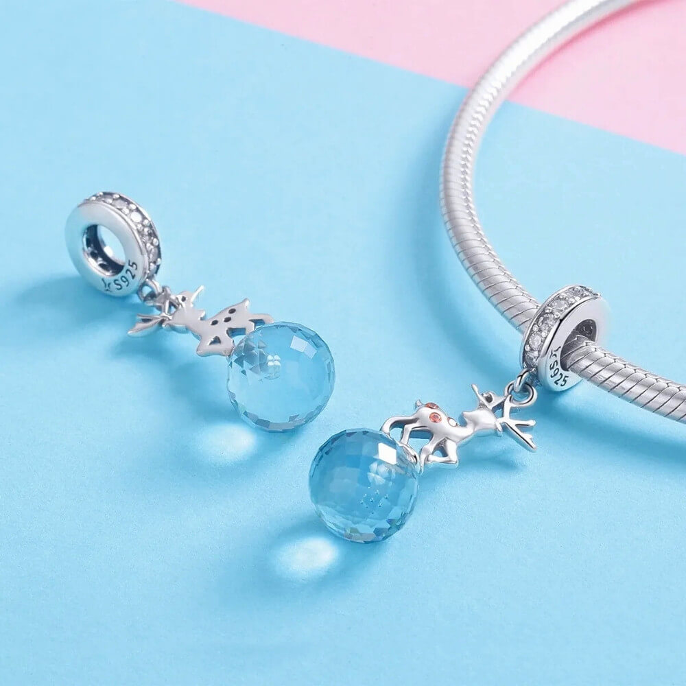 Sterling silver reindeer charm with orange gemstone spots and blue faceted crystal drop.