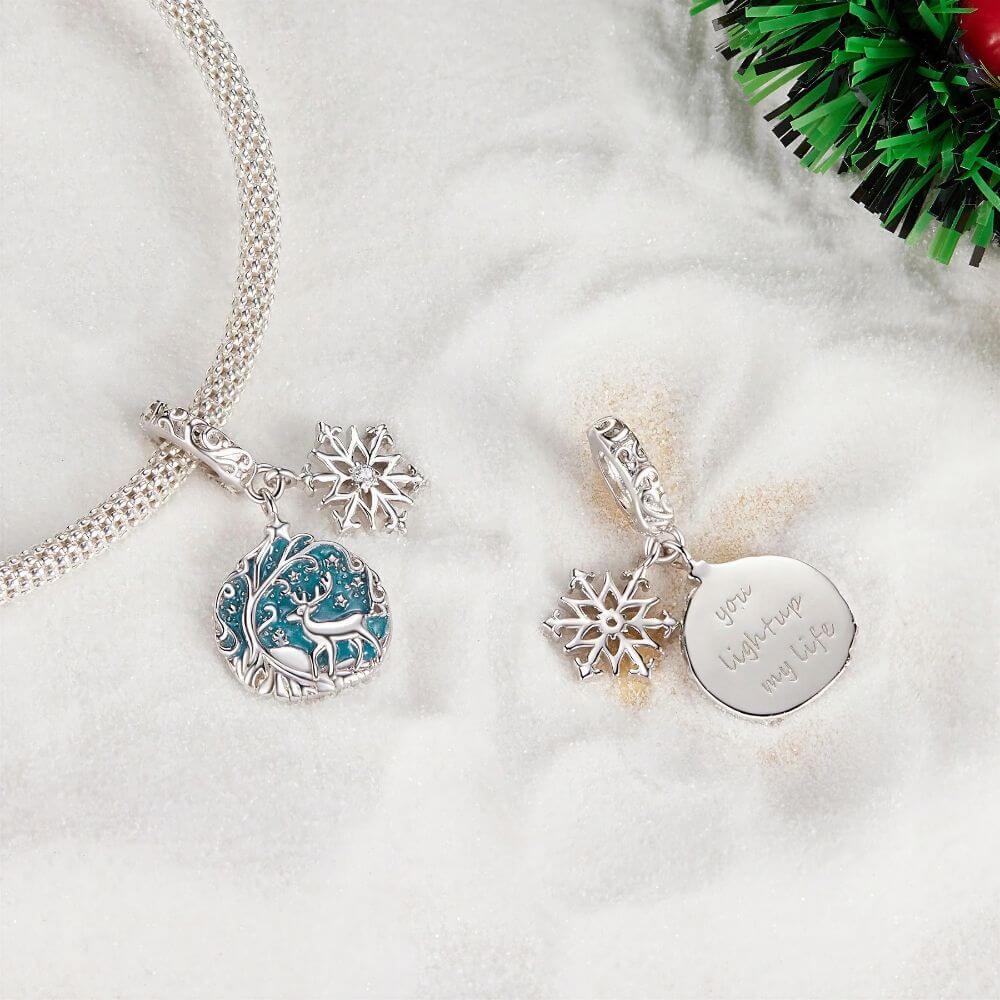 Sterling silver reindeer charm with blue enamel heart, snowflake dangle, stars, and winter forest details.