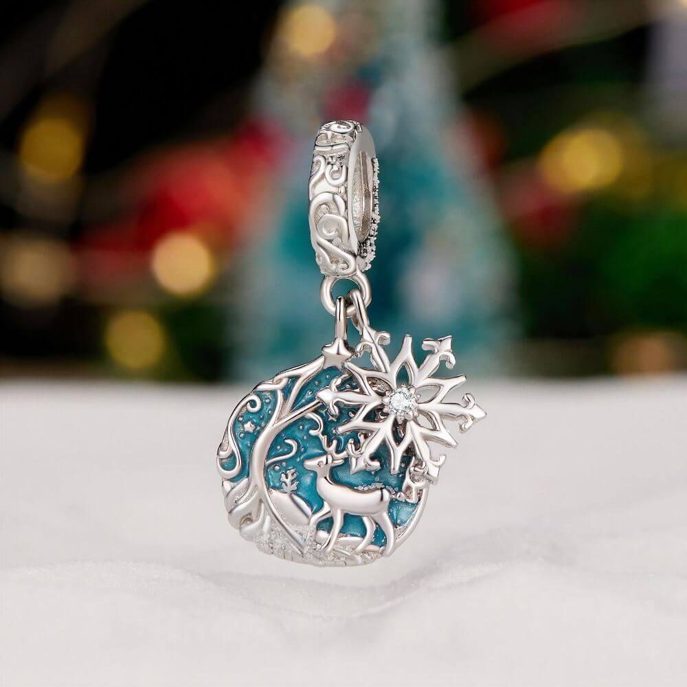 Sterling silver reindeer charm with blue enamel heart, snowflake dangle, stars, and winter forest details.