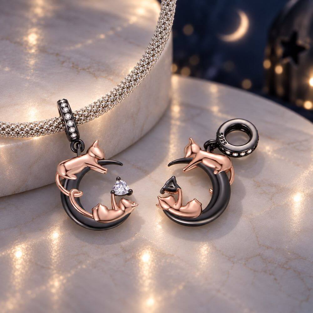 Rose gold cat moon charm with two playful cats, black crescent moon, and sparkling heart crystal detail.