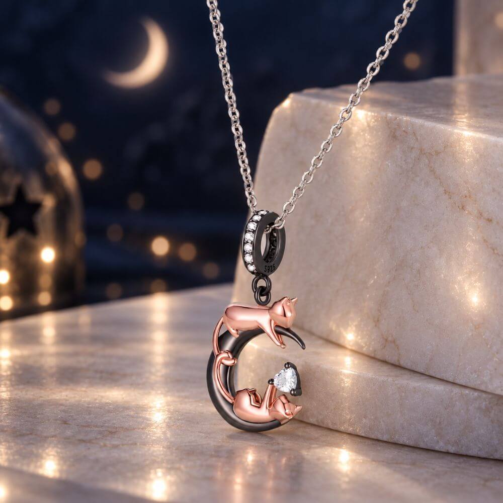 Rose gold cat moon charm with two playful cats, black crescent moon, and sparkling heart crystal detail.