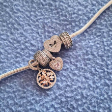 Sterling silver tree charm with rose gold branches, clear gemstones, and circular frame.
