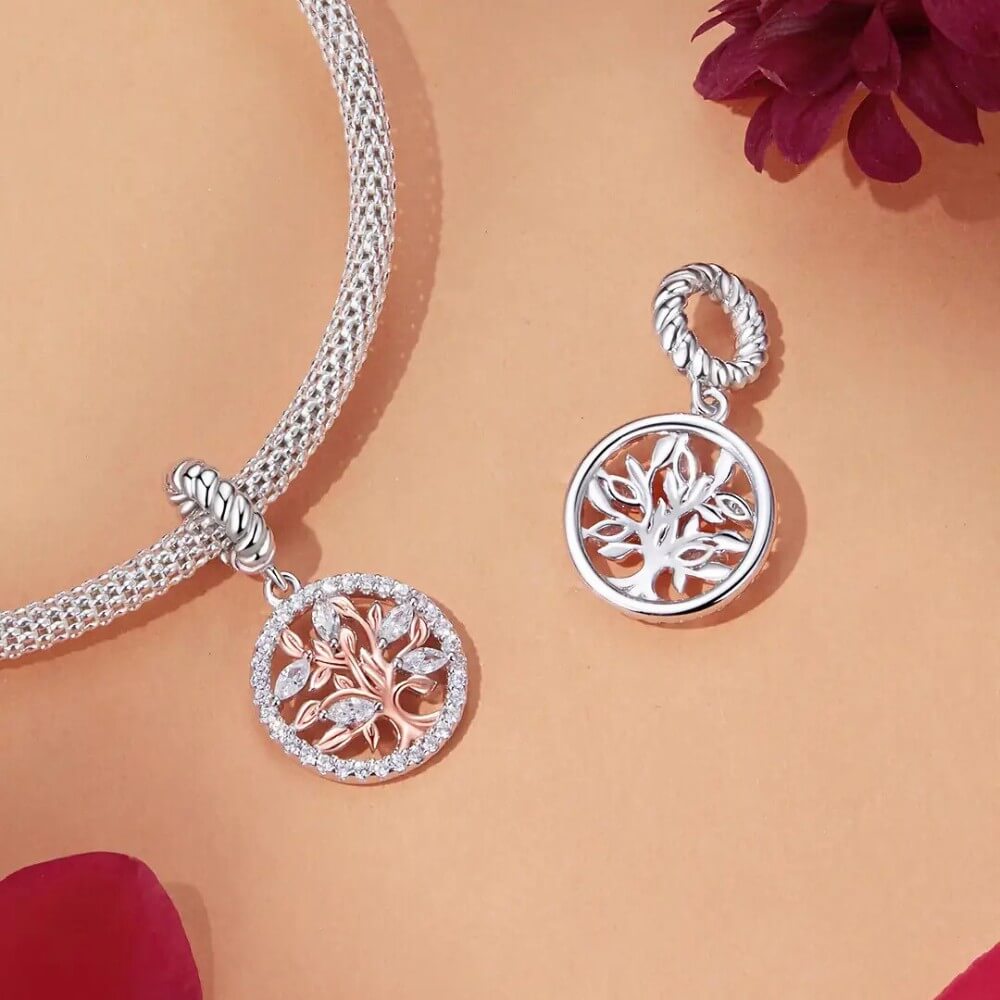 Sterling silver tree charm with rose gold branches, clear gemstones, and circular frame.