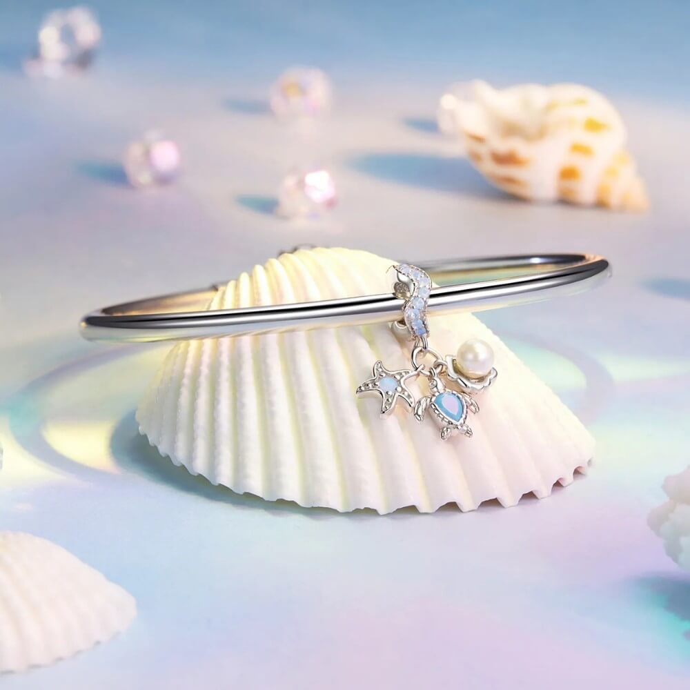 Sterling silver sea charm with turtle, pearl, and starfish details.