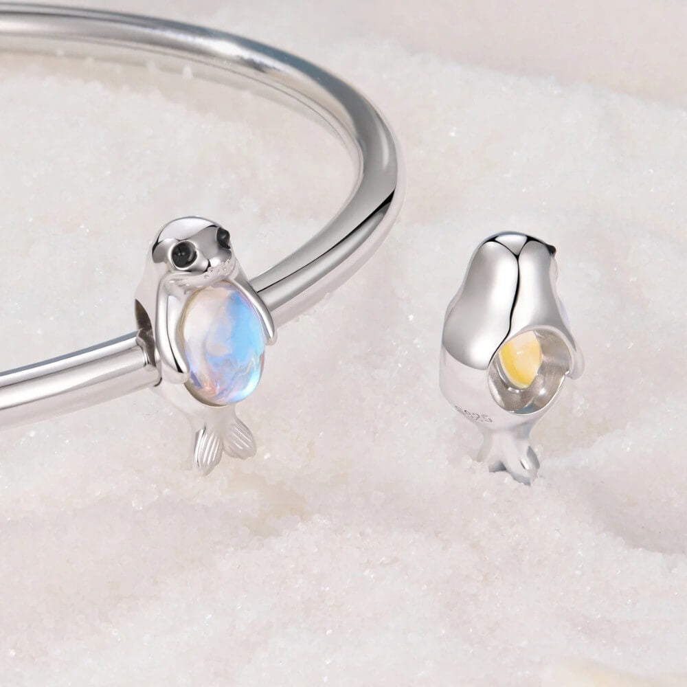 Sterling silver seal charm with iridescent opal belly and black enamel eyes.