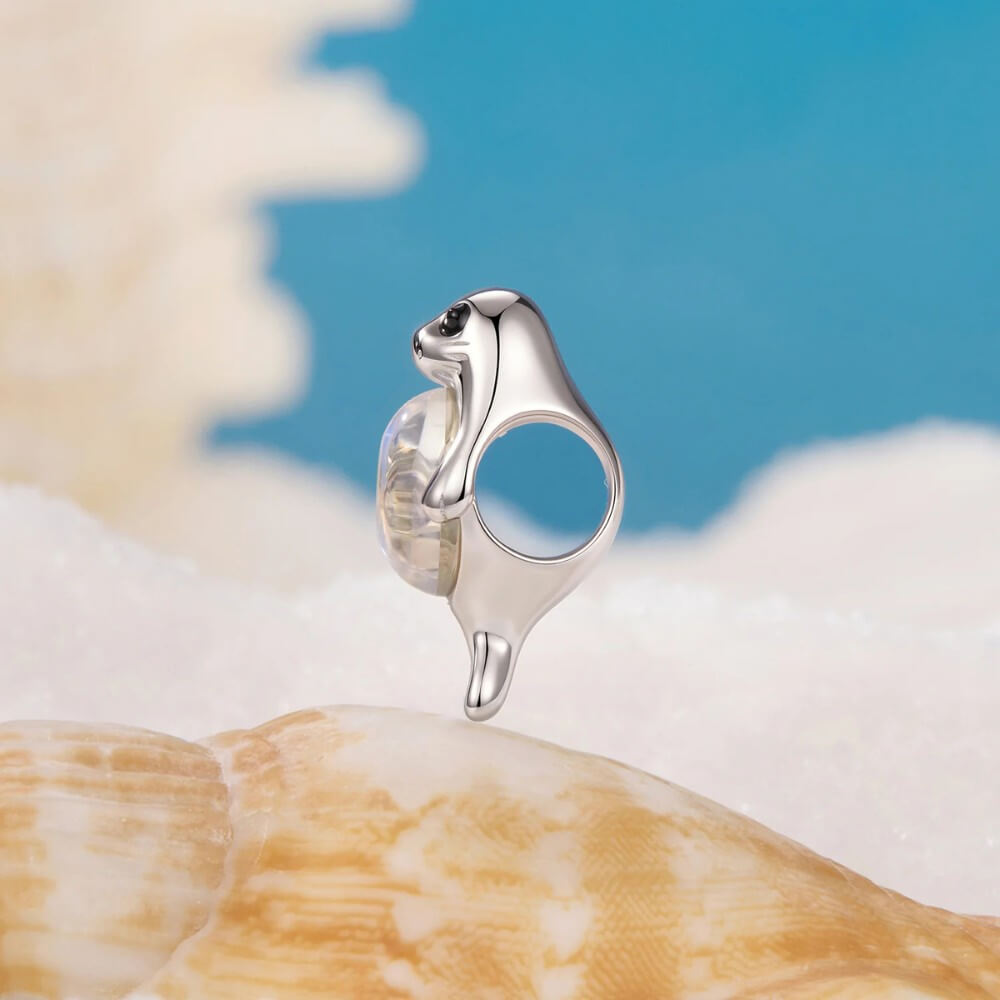 Sterling silver seal charm with iridescent opal belly and black enamel eyes.