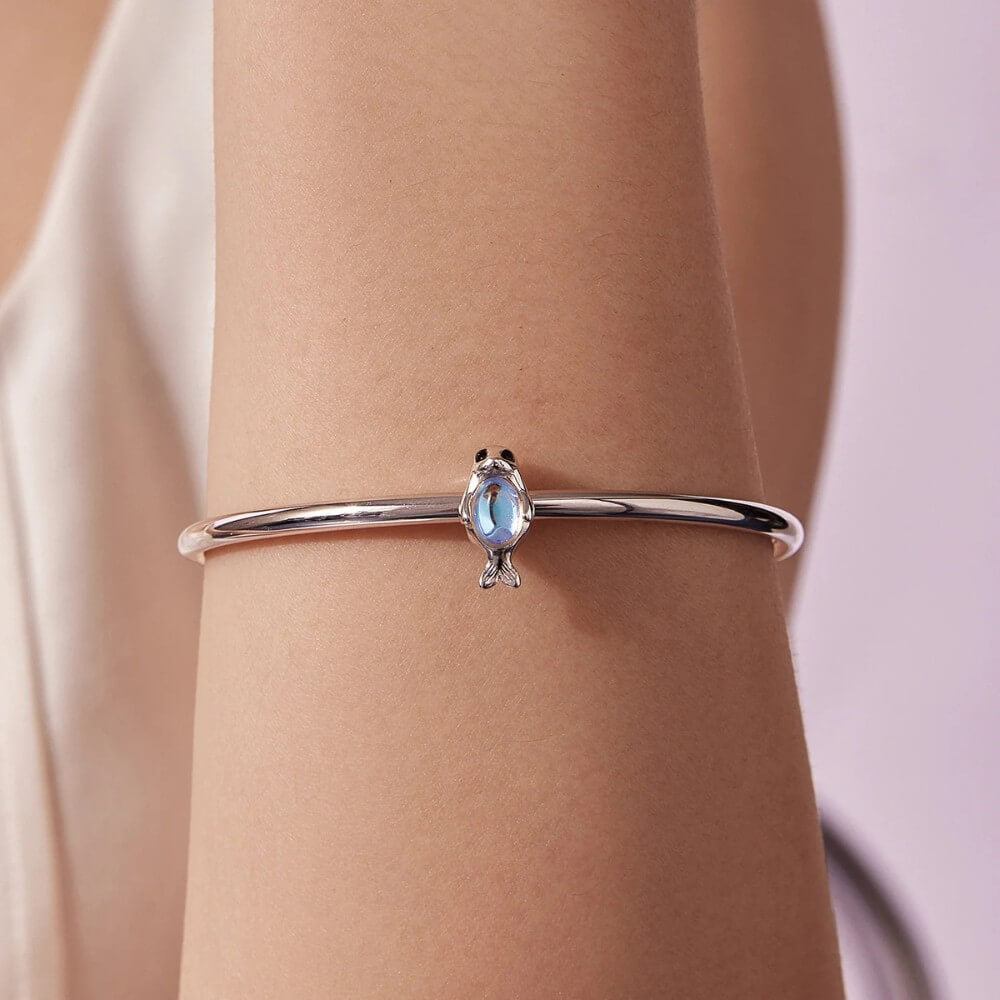 Sterling silver seal charm with iridescent opal belly and black enamel eyes.
